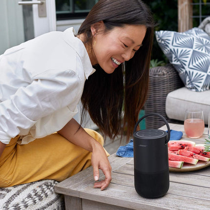 Woman sitting outdoors with a black portable speaker on a table